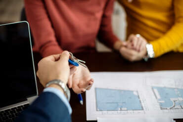 Close-up of a couple receiving keys of their new home on a meeting in the office