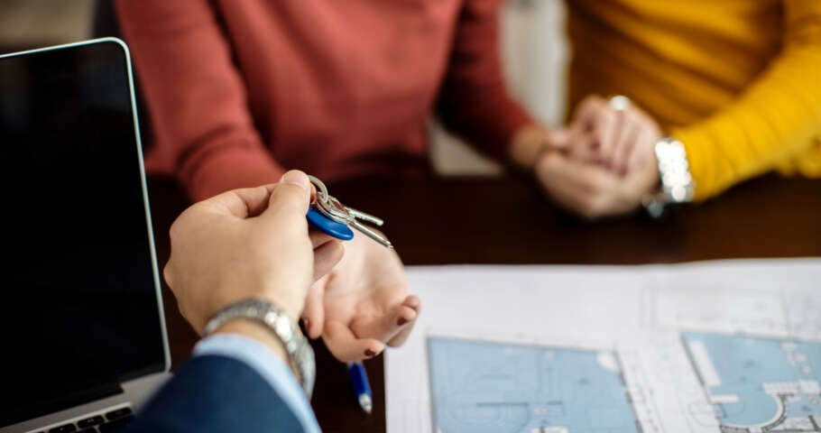 Close-up of a couple receiving keys of their new home on a meeting in the office